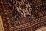 Close-up of vintage Qashqai rug, traditional stylized patterns in rich rust, navy, and ivory.