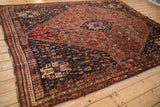 Vintage Qashqai rug section, dark navy geometric spandrel over rust field patterns.
