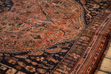 Vintage Qashqai rug showing rust field with scattered blossoms and patterned dark navy border.