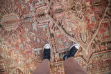 Distressed pile of the vintage Mehrivan carpet in faded raspberry, slate blue, and brown floral motifs.