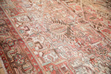 Distressed vintage Mehrivan carpet with short pile, highlighting faded raspberry, ivory, and jade geometric patterns.