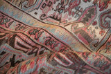 Worn pile texture reveals faded raspberry, dusty jade, and brown patterns of a Mehrivan rug.