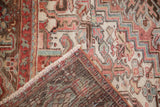 Distressed Mehrivan carpet corner, showing faded raspberry, ivory pile, tight hand knotting, and fringe.
