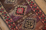 Textured close-up of vintage Kars rug border, showing pink, plum, and silver geometric patterns.
