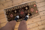 A personal, top-down view of a distressed Kars rug mat with brown and pink geometric medallions.