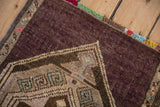 Worn knot heads and geometric border of a distressed Kars rug with a colorful fringe.