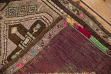 The folded corner of a vintage Kars rug reveals its aubergine back and colorful hand-knotted details.