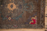 Distressed Kars rug corner with red and bronze geometric patterns, fringe, and intact selvage.