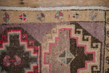 Geometric pinwheel blossoms on the sand-colored border of a distressed vintage Kars rug.