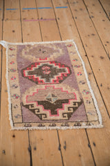 Angled view of a vintage Kars rug showing the even wear on its mauve pile and floral border.