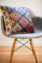Corner of early 20th century Kilim pillow, intricate geometric patterns, blue and orange tones.