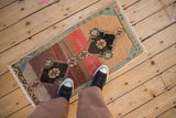 Distressed Kars rug detail: floral medallion, abrash ruby red, and seafoam green border.