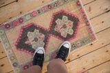 A small distressed Kars rug mat with a double medallion, shown for scale on a floor.