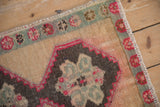 Worn pile on a distressed Kars rug showing the fuchsia floral border and stabilized color run.