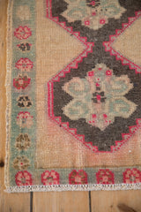 Corner view of a distressed Kars rug's floral border meeting the charcoal and fuchsia medallion.