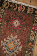Vintage Kars rug's distressed pile texture, fringe, and geometric border with copper, magenta hues.