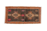 Distressed Kars rug: abrashed charcoal field, geometric stepped medallions, tangerine orange serrated border.