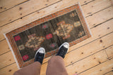 Distressed Kars rug's short pile, abrashed charcoal field, and vibrant geometric patterns.