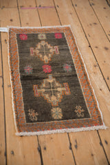 Distressed Kars rug's serrated tangerine orange border and floral motifs on charcoal pile.
