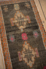 Distressed vintage Kars rug with abrashed charcoal field, geometric medallion, bright raspberry floral.