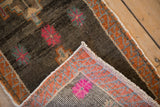 Folded corner of distressed Kars rug, revealing short pile, vibrant raspberry floral, and hand knotted foundation.