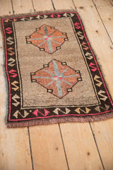Distressed Kars rug corner, beige pile, fringe, and geometric brown border with pink accents.