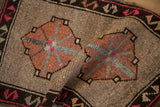 Geometric copper and magenta medallions on a folded, distressed Turkish Kars rug.