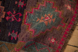 Textured distressed Kars rug showing fuchsia geometric motifs and plum, teal abrash.