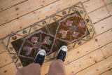 Distressed pile of a vintage Kars rug, showing primitive quatrefoil floral motifs and abrashed ground.