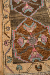 Distressed Kars rug detail: abrashed brown field with dusty mauve, slate blue quatrefoil motifs, red-outlined vine border.