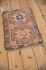 Vintage distressed Kars rug corner with sand, pink, teal geometric border and fringe.