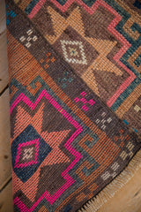 Folded Vintage Distressed Kars rug detail: vibrant pink, sky blue, copper geometric patterns and fringe.