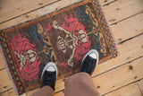 Vintage distressed Kars rug mat with rose and teal motifs, shown for scale.