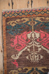 Corner detail of a vintage Kars rug with a diamond border, rose motif, and even wear.