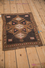 Distressed vintage Kars rug mat from an angle, highlighting its coffee brown and pink geometric design.