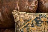 Antique Turkish rug pillow with worn blue, gold pattern and muted lime green piping.