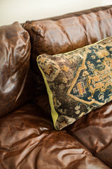 Intricate geometric design and aged texture of an antique Turkish rug pillow, with lime green piping.