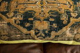Close-up of antique Turkish rug fragment on pillow, dark blue, gold geometric pattern, worn.