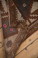 Distressed hand-knotted texture of a vintage Kars rug with bronze and pink geometric details.