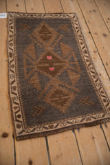 Distressed Kars rug's geometric medallion detail, showing charcoal, bronze, and pink accents.