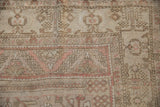 Distressed Oushak rug corner with faded dusty rose, beige, and brown geometric patterns.