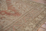 Corner of distressed vintage Oushak rug, highlighting faded dusty rose field and intricate neutral borders.