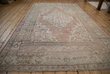 Distressed vintage Oushak rug corner detail with faded dusty rose and intricate border designs.