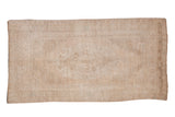 Vintage distressed Oushak runner with a faded oversized medallion in soft beige, ivory, and silver.