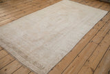 Angled view of a vintage Oushak runner with a lustrous low pile in soft beige and ivory tones.