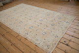 Distressed texture of vintage Sparta carpet, showing sand and dusty navy floral motifs.