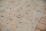 Even wear across distressed beige and antique ivory pile with dusty navy floral motifs.