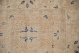 Distressed texture of the Sparta carpet with worn beige pile and dusty navy stylized motifs.