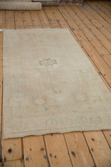 Angled view of a distressed Oushak runner showing the even wear across its pale silver and sea foam green design.