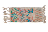 Moroccan rug mat with playful abstract designs in turquoise, dusty rose, and faded violet.